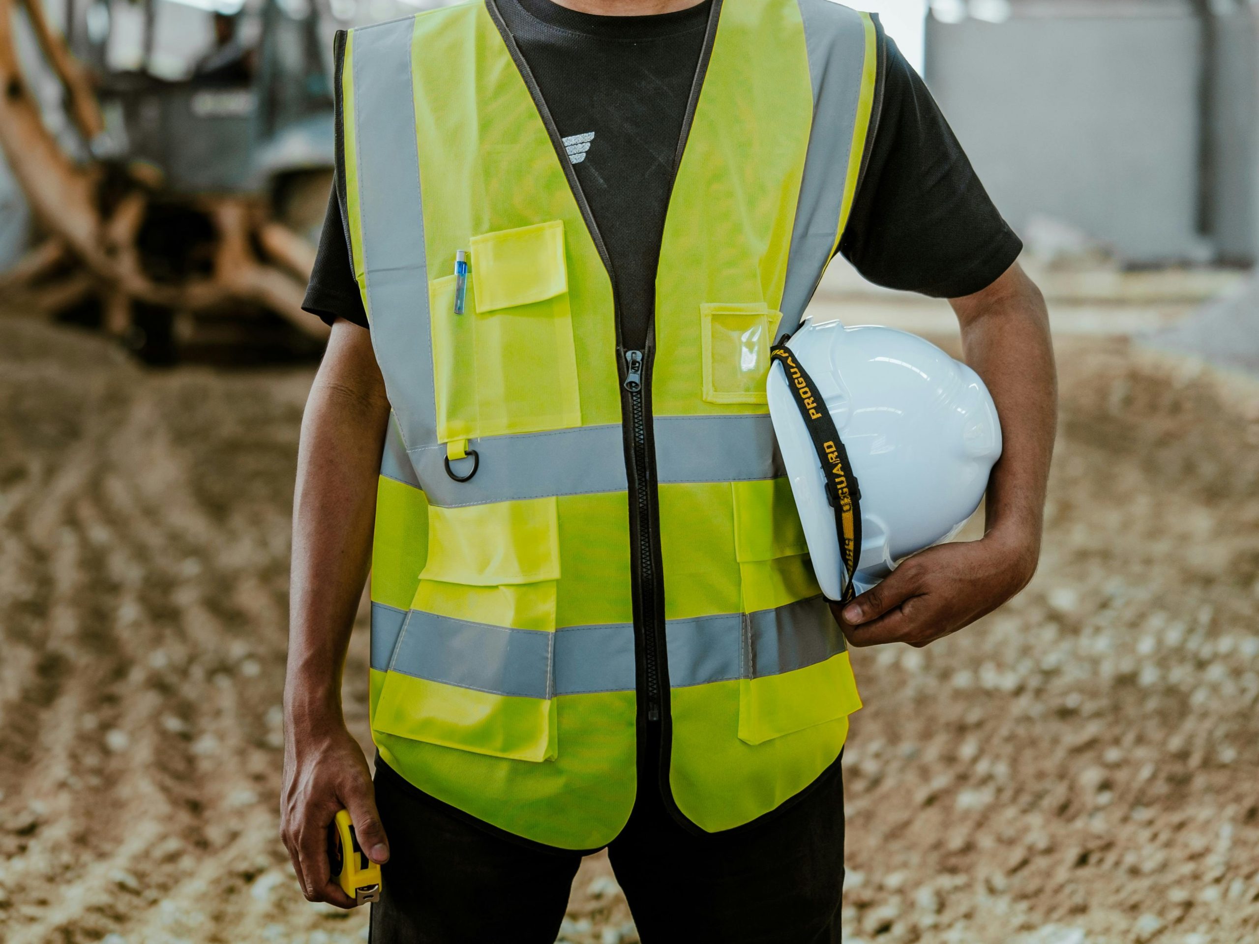 Hombre extranjero, obrero de una construcción, trabajando en una obra con maquinaria.